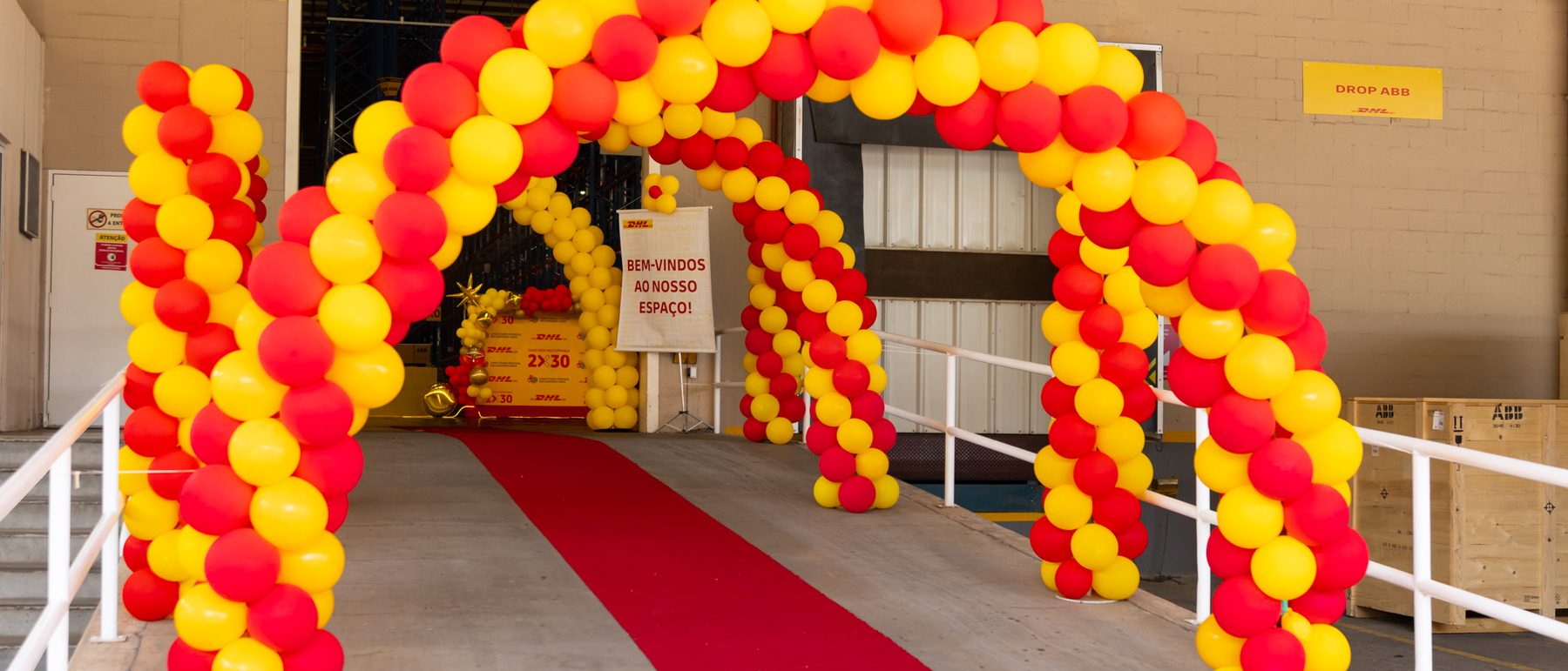 Arco de balões e tapete vermelho na entrada do evento corporativo montado dentro da empresa