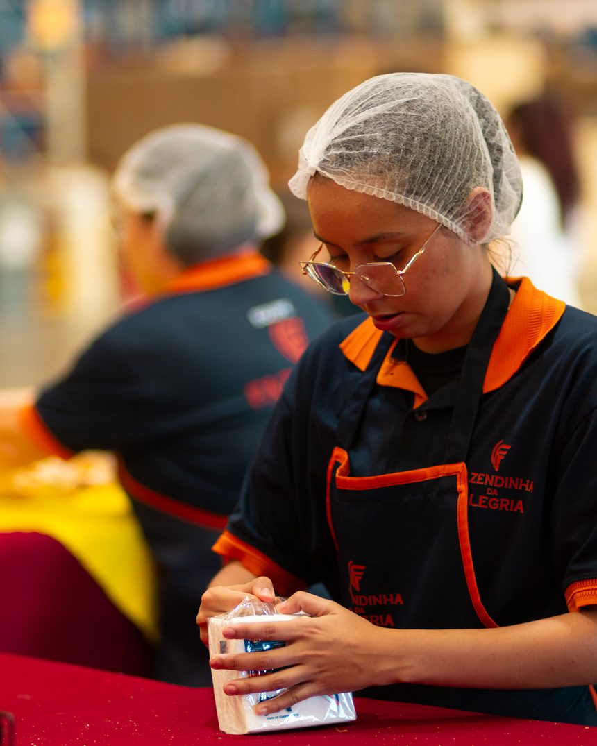 Colaboradora uniformizada da Fazendinha da Alegria operando a barraca de alimentação do evento