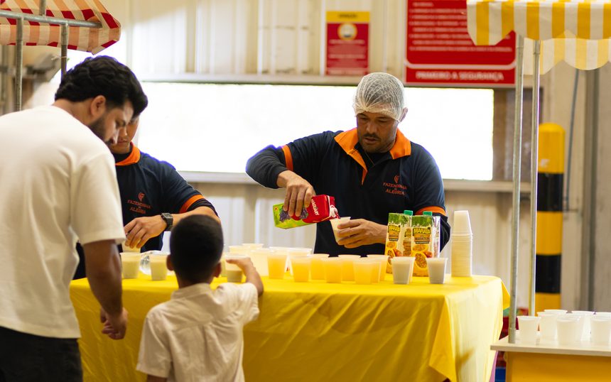 Equipe da Fazendinha da Alegria servindo uma criança na barraca do evento para filhos de colaboradores