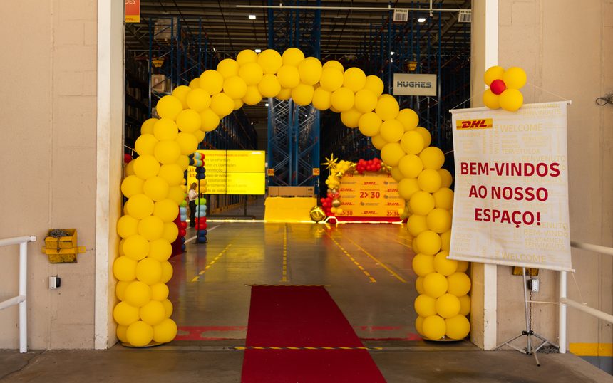 Arco de balões e tapete vermelho na entrada do evento, com placa de boas-vindas ao espaço